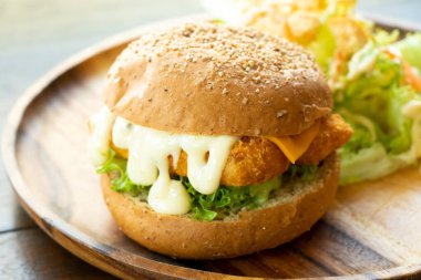 Ahşap tabakta sebze salatalı kızarmış balık fileto burger.