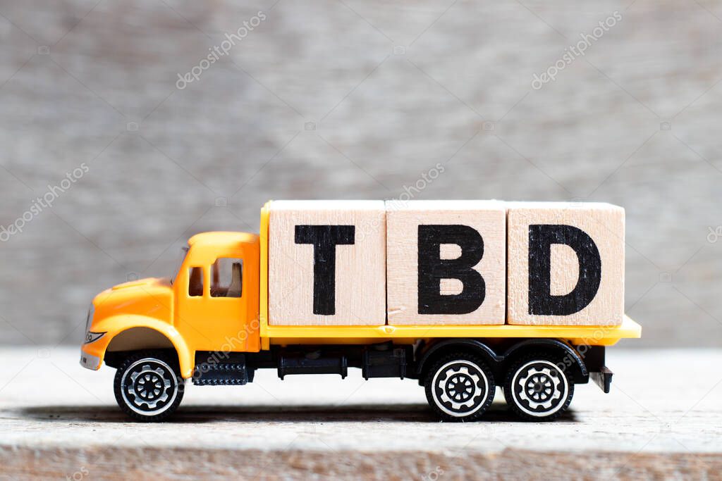 Truck hold letter block in word TBD (Abbreviation of to be defined, discussed, determined, decided, deleted or declared) on wood background