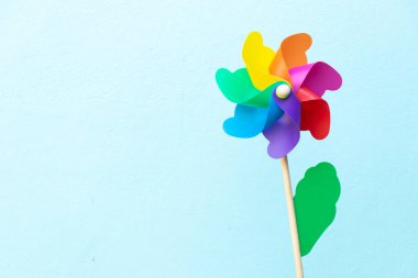 Mavi zemin üzerinde renkli oyuncak plastik yel değirmeni