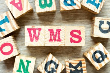 Kelime WMS ile alfabe harf bloğu (depo yönetim sisteminin kısaltılmışı) ve ahşap zemin üzerinde başka bir