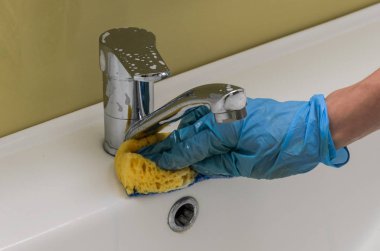 Tesisatçı ve bir musluk banyo ev kimyasal madde ile bir bez ile eldiven bir kadında yıkıyor