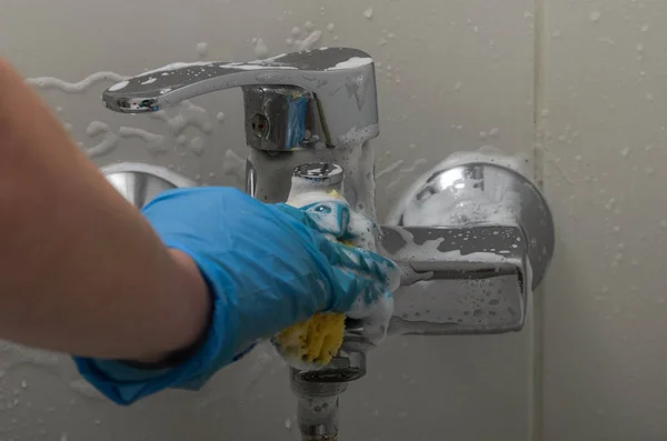 一个戴手套的女人在浴室里用抹布洗水管工和水龙头 还有家用化学品 — 图库照片