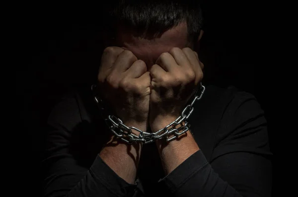 一个被锁在链子上的男人被囚禁在一个黑色的背景上 — 图库照片