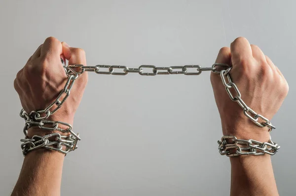 The prisoner's hands are bound in metal chains