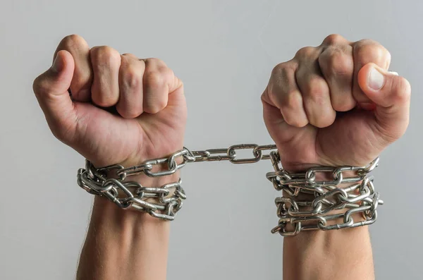 The prisoner\'s hands are bound in metal chains