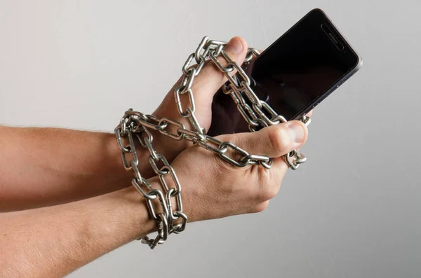 Mobile phone chained to the hands of a man, telephone dependence