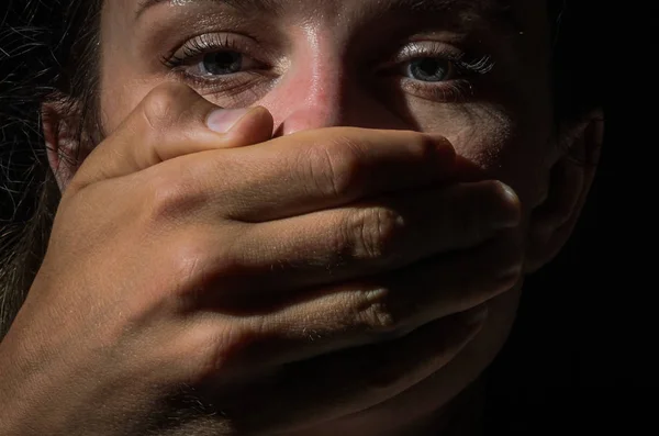 A man\'s hand covers a woman\'s mouth, domestic violence