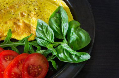 Omlet rucola, fesleğen ve domates ile bir plaka üzerinde