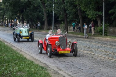 Lviv, Ukrayna - Haziran 2018: Erkek ve kadın kırmızı vintage retro cabriolet Araba Fiat şehir sokaklarında sürme