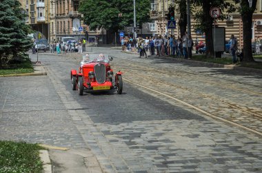 Lviv, Ukrayna - Haziran 2018: Erkek ve kadın kırmızı vintage retro cabriolet Araba Fiat şehir sokaklarında sürme