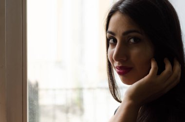 Bir pencere oturan bir genç çekici kız portresi