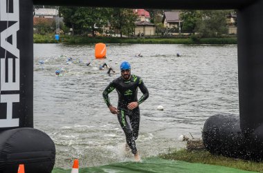 Ukrayna, Lviv - Eylül 2018: Bir atlet takım elbiseli hidro-sudan yüzdükten sonra bir triatlon yarışma sırasında çalışır