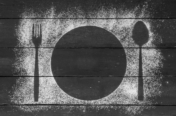 Drawing of flour on a wooden background with a fork, spoon and plate