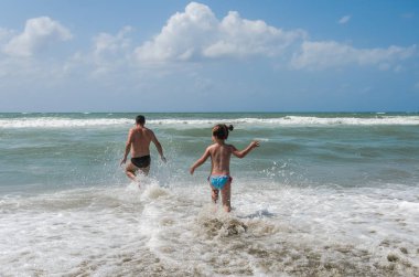 Genç baba ve kızı yüzmek ve yaz tatillerinde denizde oyun