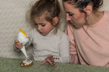 Anne ve kızı gingerbread buzlanma ile süsleyin