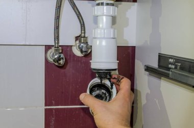 Tesisatçı sifon lavabonun altında kanalizasyon drenaj temizler