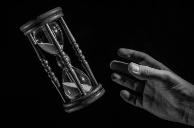 İnsan eli zaman kum saati izole üzerinde siyah arka planda yakalamak istiyorum