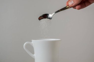 Beyaz bir kupa bir el sarılmak şeker