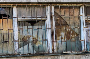 Eski bir terk edilmiş evde parmaklıkların arkasında kırık pencere