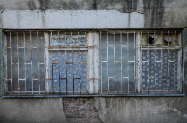 Eski bir terk edilmiş evde parmaklıkların arkasında kırık pencere