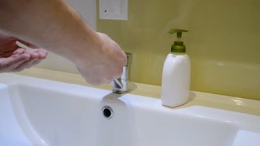 Bir adam ellerini lavaboda banyoda sıvı sabun ile yıkar
