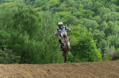 Lviv, Ukrayna - Mayıs, 2019: Atlet motosiklet yarışçısı bir motokros pistinde enduro motosiklete biniyor ve atlıyor