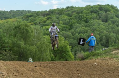 Lviv, Ukrayna - Mayıs, 2019: Atlet motosiklet yarışçısı bir motokros pistinde enduro motosiklete biniyor ve atlıyor