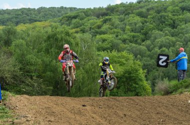 Lviv, Ukrayna - Mayıs, 2019: Atlet motosiklet yarışçısı bir motokros pistinde enduro motosiklete biniyor ve atlıyor