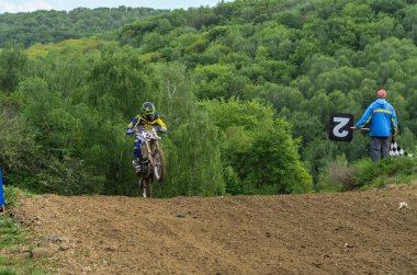 Lviv, Ukrayna - Mayıs, 2019: Atlet motosiklet yarışçısı bir motokros pistinde enduro motosiklete biniyor ve atlıyor
