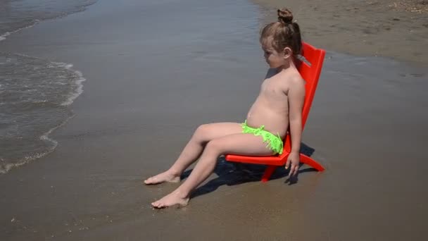 Bambina Affascinante Seduta Una Sedia Riva Mare Una Spiaggia Sabbia — Video Stock