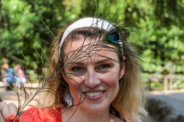 Tavus kuşu tüyü olan genç, neşeli, güzel bir kızın portresi