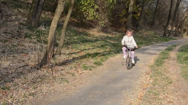 女の子の子供は秋の公園で自転車に乗ることを学ぶ — ストック動画