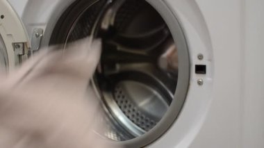 Hizmetçi kirli çamaşırları çamaşır makinesine atıyor.