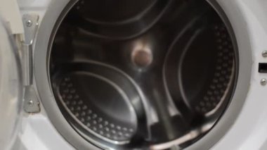 Hizmetçi kirli çamaşırları çamaşır makinesine atıyor.