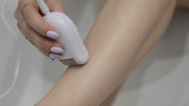 Kadın elektrikli epilatörle bacaklarını sarıyor.