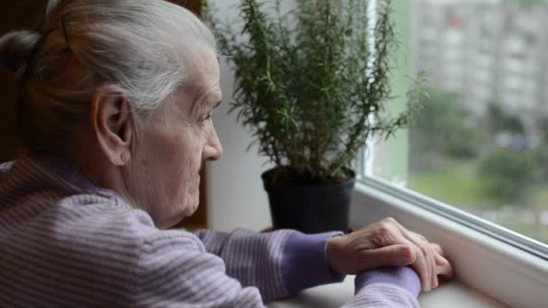 Une Femme Âgée Regarde Par Fenêtre Agite Main — Video