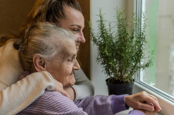 Elderly Woman Grandmother Looks Out Window Granddaughter Approaches Her Hugs Stock Image