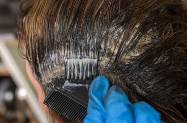 Usta kuaför saçını saç boyasıyla boyar.