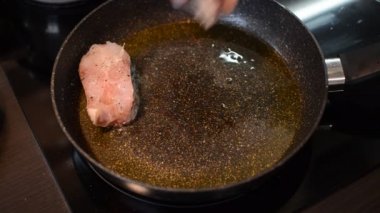 İndüksiyon sobasında tavada kızarmış balık bifteği.