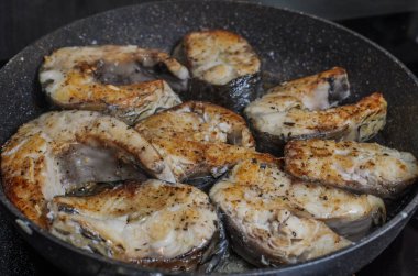 İndüksiyon sobasında tavada kızarmış balık bifteği.