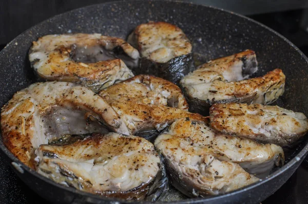 İndüksiyon sobasında tavada kızarmış balık bifteği.