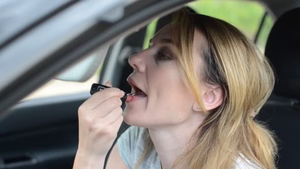 Młoda Urocza Dziewczyna Nakłada Szminkę Usta Podczas Jazdy Samochodem — Wideo stockowe