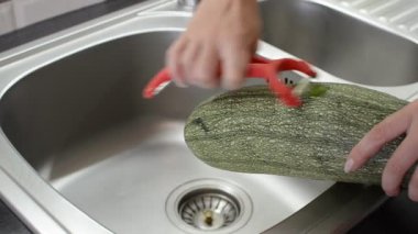 Aşçı kabuğundan bir bıçakla büyük bir kabak soyar.