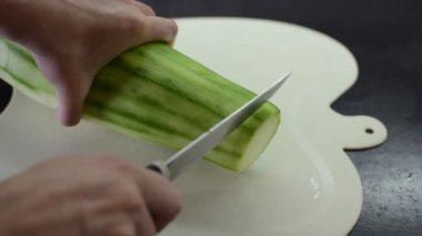 Aşçı büyük bir kabağı dilimlere ayıran bıçakla kesme tahtasıyla keser.