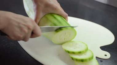 Aşçı büyük bir kabağı dilimlere ayıran bıçakla kesme tahtasıyla keser.