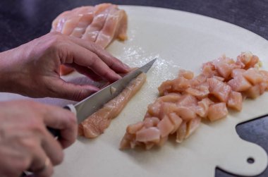  Şef kesme tahtasındaki bıçakla tavuk göğsünü kesiyor.