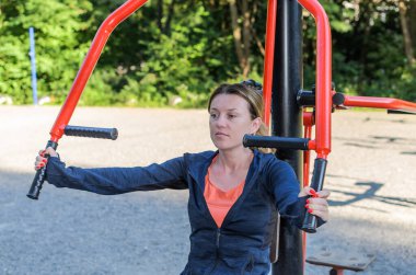 Stadyumdaki egzersiz makinesinde spor yapan genç kız.