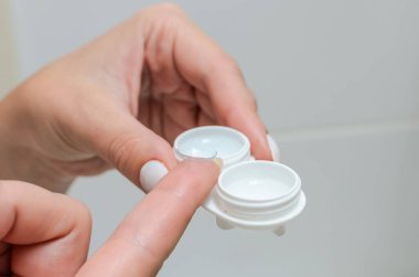 Görüş düzeltmesi için kontakt lensleri siler ve kontak lens kabına yerleştirir