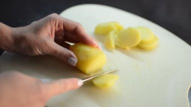 Aşçı kesme tahtasındaki bıçakla haşlanmış patatesleri keser.