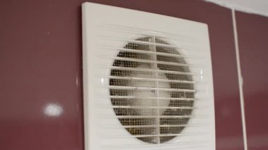 Efendi, servis için banyoda duvara monte edilmiş bir vantilatörü söküyor.